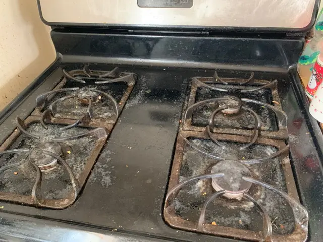 Dirty black stovetop with burnt-on grease before deep cleaning